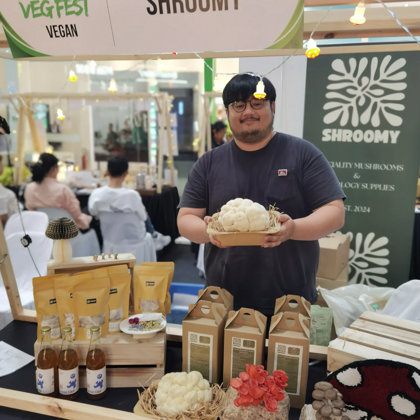 A grower holding a fresh harvest of white mushrooms at the Shroomy booth